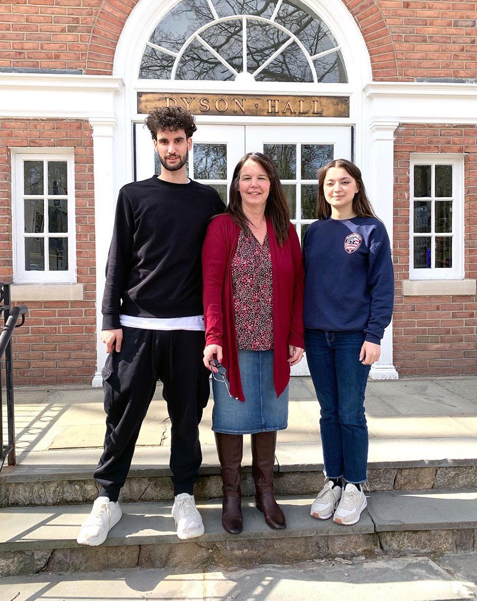's Biology Professor Nancy Krucher standing on the steps in front of Dyson Hall with students Michael Feretti and Anastasiia Vaska who assisted in cancer treatment resistance research