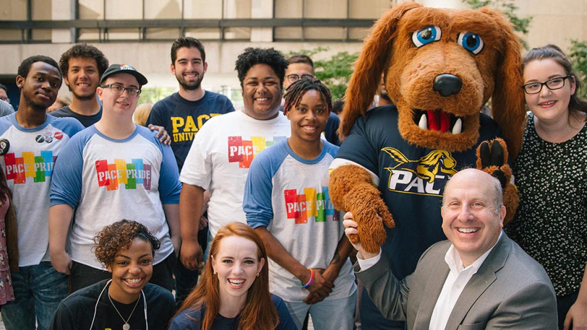 Presiden Krislov smiling at the camera, standing with a group of students and T-Bone, 's mascot.