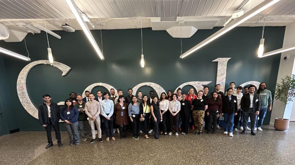  Seidenberg students, faculty, and staff posing in front of the Google logo at the Google New York City office.
