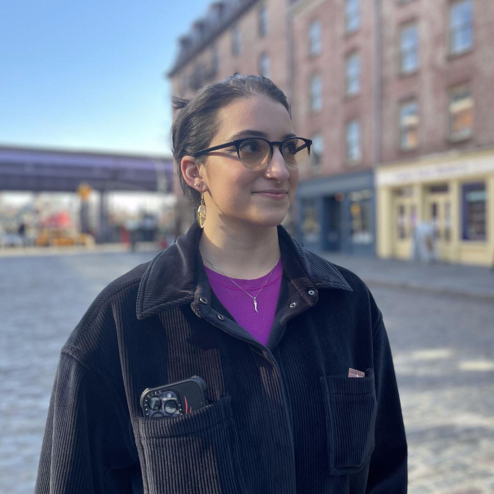  Student Lauren DeMaio standing in front of old buildings in Seaport, NYC.