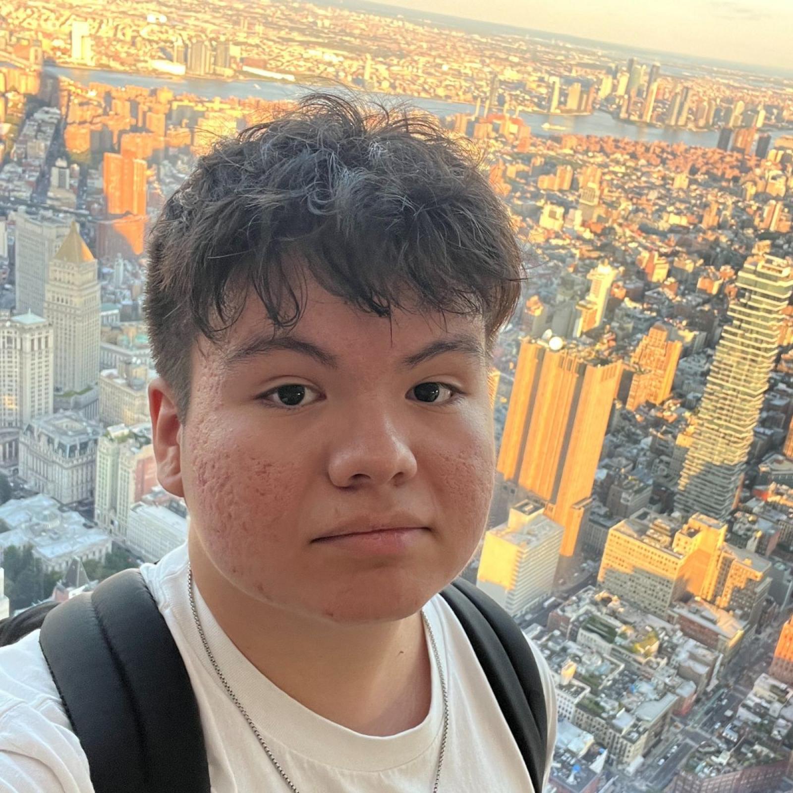  student Daniel Ramos taking a selfie while overlooking the NYC skyline at sunset.
